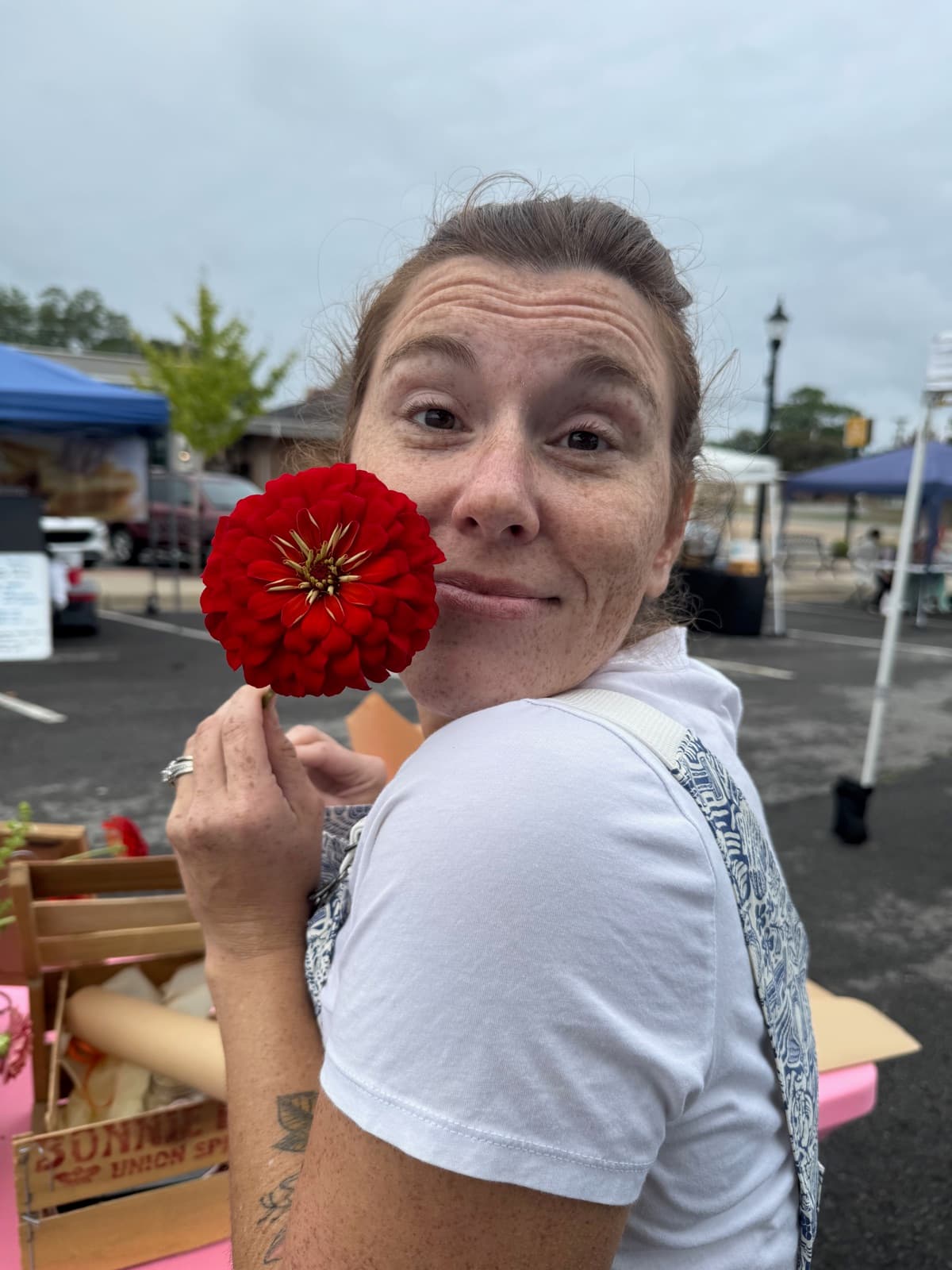 Lauren playfully holding a red zinnia